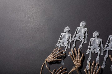 Multiple skeleton toys and skeleton hands with copy space on grey background - Powered by Adobe