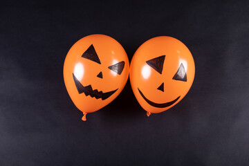 Two halloween pumpkin printed balloons with copy space on black background - Powered by Adobe