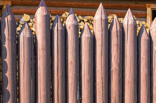 Background Of Logs. The Fence Is Made Of Rounded Logs. Wooden Architecture In The Countryside. Logs Are Treated With Impregnation From Mold And Fire.