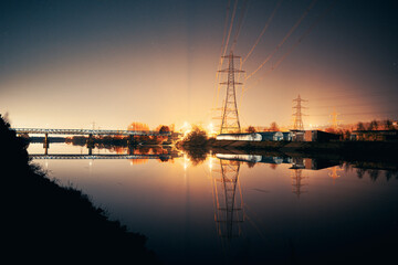 Fototapeta na wymiar Newburn UK: 6th march 2022: Newburn Bridge Riverside at night electric pylons, rowing club and still river with warm glowing industrial light