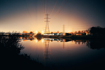Newburn UK: 6th march 2022: Newburn Bridge Riverside at night electric pylons, rowing club and still river with warm glowing industrial light