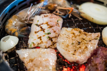 Cooking barbecue and grilled over charcoal on stove. Raw pork slice and seafood for barbecue or...