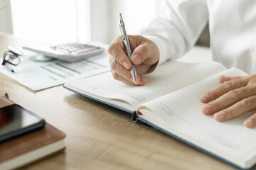 Fototapeta premium Business man writing a business investment plan, man wearing white shirt Work on the desk in the office
