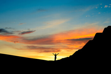 Silhouette of strong confidence young woman standing alone and open arms under the sunrise on top...
