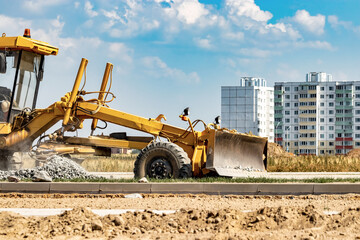 Road grader at the construction site. Powerful construction machine for ground leveling and excavation. Close-up. Professional construction equipment.
