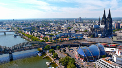 Aerial view of Cologne city on a sunny day. Famous landmark of gothic architecture Cologne Cathedral and Hohenzollern Bridge ft. central train station, Rhine River in North Rhine-Westphalia, Germany