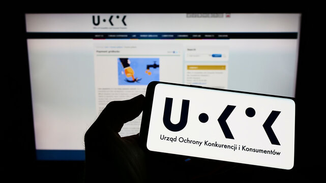 Stuttgart, Germany - 09-04-2022: Person holding cellphone with logo of Polish competition authority UOKiK on screen in front of webpage. Focus on phone display.