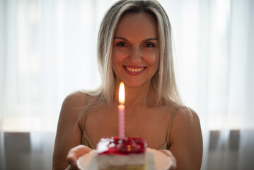 Young woman holding birthday cake , selective focus. Birthday celebration concept.  Joyful girl...
