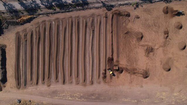 Aerial of yellow tractor spreading compost mixture on a farm