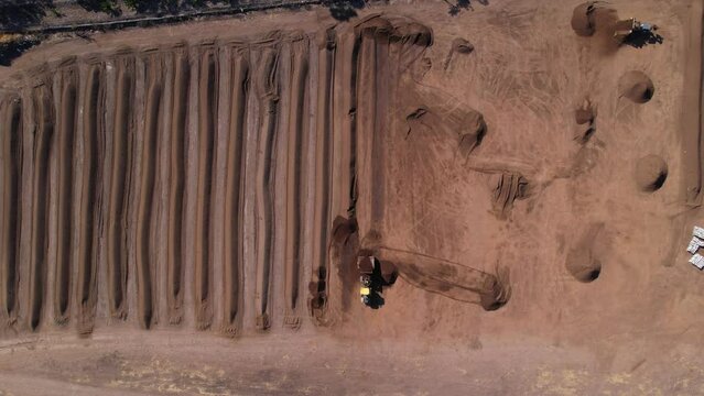 slow aerial push in on compost being processed by a yellow tractor on a fram