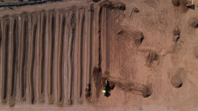 static aerial shot of yellow tractor processing compost mixture on a farm in mexico