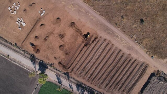 Aerial of yellow tractor dropping compost mixture into a field