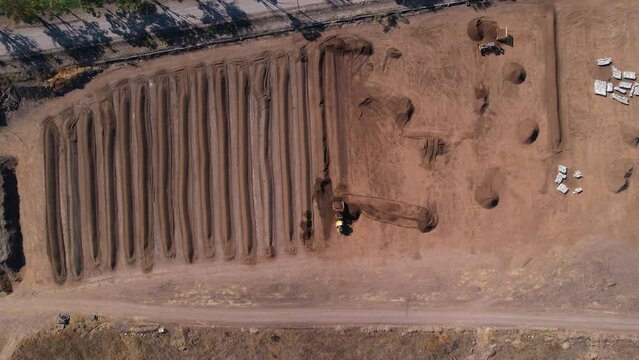 Aerial drop down of a yellow tractor processing compost mixture on a farm in mexico