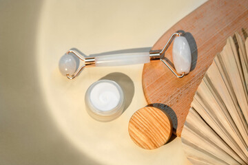 op view of facial roller for massage on wooden slice.Pastel colors,eco friendly concept.