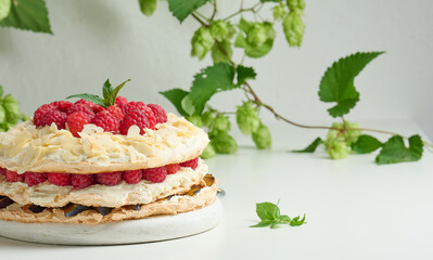 Round meringue pie with fresh raspberries on a white background