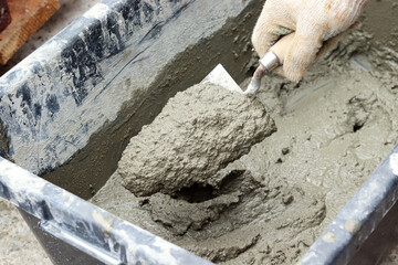 Mixing concrete by hand. Scooping up the concrete mixture with a trowel. selective focus