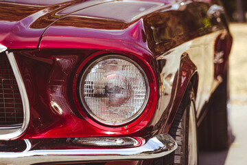 Vintage retro car with close-up on headlights. Front view red muscle car with chromed parts