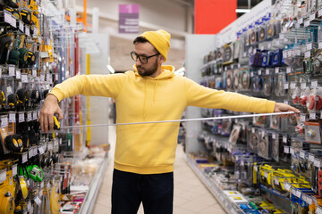 a young man chooses a construction roulette in a shop not for building goods