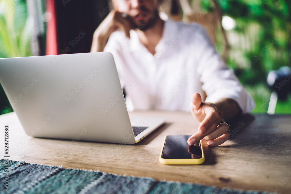 Poster blurred male it professional checking received notification on modern cellphone while working remote
