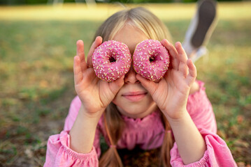
the child eats a donut.
delicious pink donut. Bitten donut. Girl with donuts. Happy girl with...