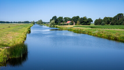 Fototapeta na wymiar Blue water wih green nature surroundings at the banks of the river, Netherlands