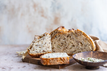 Sliced loaf of artisan sourdough bread with multigrain seeds. Tartine with honey and seeds, concrete background.