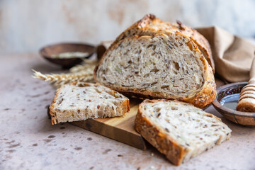 Sliced loaf of artisan sourdough bread with multigrain seeds. Tartine with honey and seeds, concrete background.
