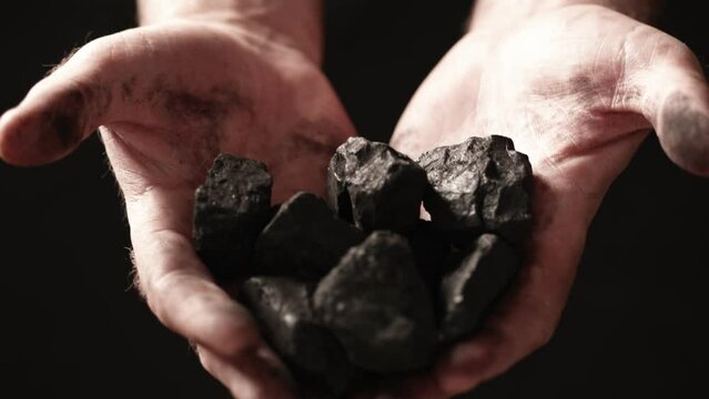 A miner shows the pieces and nuggets of coal in his hands.