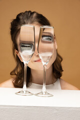 Modern art photography. Beautiful girl's face through wine glasses. Object distortion, optical...