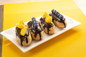 eclairs with blueberries and peach on a yellow background. food concept. dessert