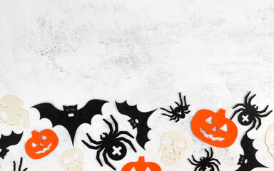 Minimalsitic halloween background with skulls,pumpkins,bats abd spiders on white concrete background. Invitation or card for october 31.Copy space