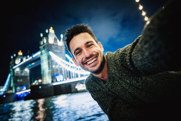 Happy young man taking selfie in Tower Bridge, London - Handsome guy smiling at camera on city...