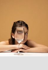 Modern art photography. Beautiful girl's face through wine glass. Object distortion, optical...