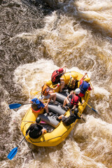Top view of a rowers team with an oars overcomes rapids on a stormy river on an inflatable rafting...