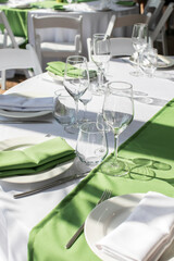 The dining table in the restaurant is prepared for the festive event. The tables are covered with a white tablecloth and a path of green textiles