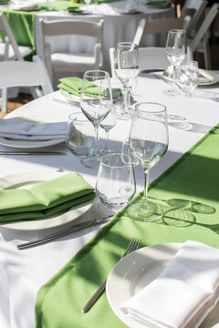 The Dining Table In The Restaurant Is Prepared For The Festive Event. The Tables Are Covered With A White Tablecloth And A Path Of Green Textiles