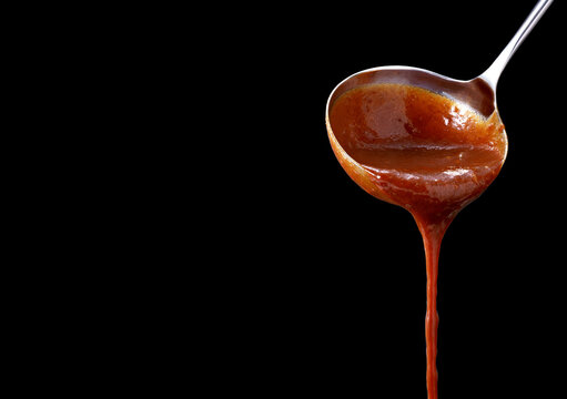Pouring chili sauce, isolated on black background