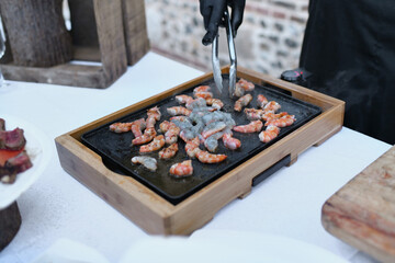 The chef prepares the shrimps on the plancha