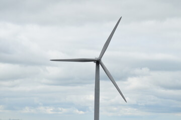 Close up of a wind turbine with a grey sky background. 