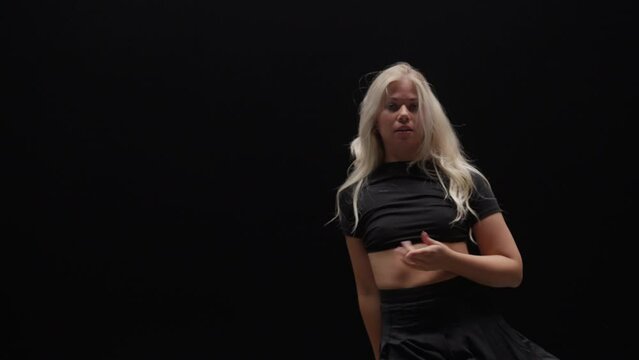 Alluring Young Woman Dancing in Studio Against Black Background