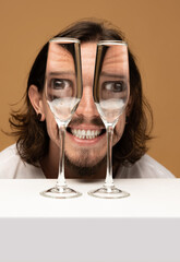 Happy man's face through wine glasses. Object distortion, optical illusion. Minimalistic...