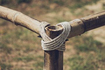 Coarse rope wrapped around wooden pole in vintage color.Blured background with a natural sunlight