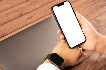 Smartphone and smart watch, close up over shoulder view of smartphone and smart watch. Woman...