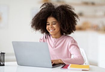 Obraz na płótnie Canvas Adorable black girl doing homework, using laptop