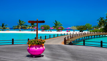Landscape on Maldives island, luxury water villas resort and wooden pier. Beautiful sky and ocean and beach with palms background for summer vacation holiday and travel concept. Luxury travel.