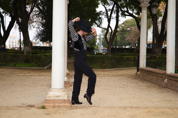 gypsy man dancing flamenco with long hair and beard in a park next to some marble columns. He is...