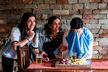 Familia en la previa antes del mundial de futbol, sufriendo, llorando . con picadas y cervezas,   los colores celeste y blanco, luz natural, riendo.