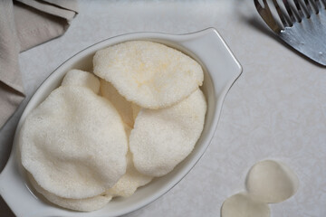 Crispy prawn crackers, deep fried, are served in an oval dish as a starter. Top view.