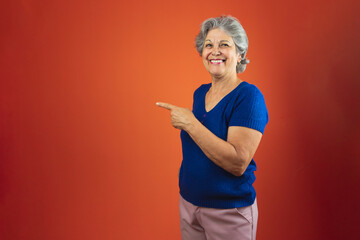 Fototapeta na wymiar Portrait of Smiling Woman With Gray Hair and Blue T-Shirt, Isolated Over Orange Background