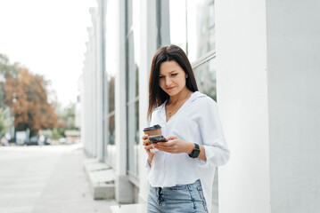 Young woman holding a paper cup of coffee outdoors